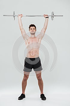 Young healthy man athlete doing exercises with barbell
