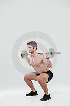 Young healthy man athlete doing exercises with barbell