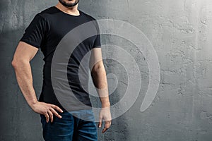 Young healthy man with black T-shirt on concrete background with copyspace for your text