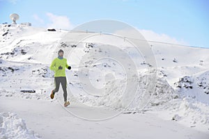 Young healthy sport man running in snow mountains in trail runner hard workout in winter
