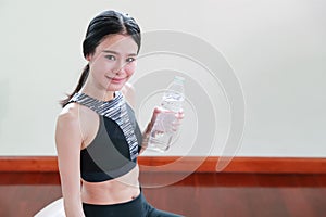 Young healthy and sporty woman drinking water in gym