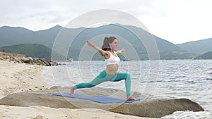 Young healthy sporty woman practicing yoga on the beach at sunset.