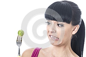 Young Healthy Woman with Disgusted Expression with Distaste to a Brussels Sprout on a Fork