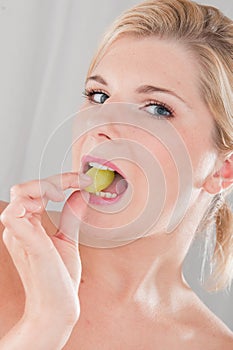 Young healthy woman eating grapes