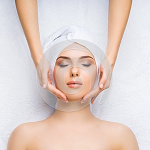 Young and healthy woman gets massage treatments for face, skin and neck in the spa salon. Health, wellness and