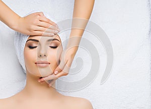Young and healthy woman gets massage treatments for face, skin and neck in the spa salon. Health, wellness and