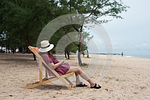 Young healthy woman with hat relax on chair at the sand beach