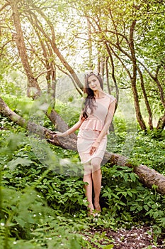 Young healthy woman outdoors portrait. Beauty girl in flowers wreath in blossom garden in sunny spring day