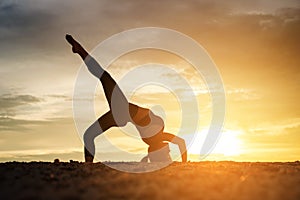 Young healthy woman practicing yoga on the beach exercise at sunset time