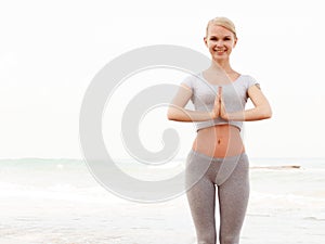 Young healthy woman practicing yoga on the beach at sunrise