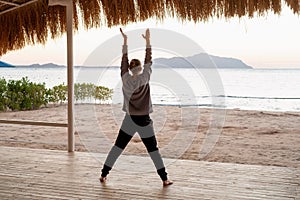 Young healthy woman practicing yoga on the beach at sunrise