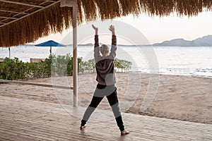 Young healthy woman practicing yoga on the beach at sunrise