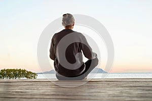 Young healthy woman practicing yoga on the beach at sunrise