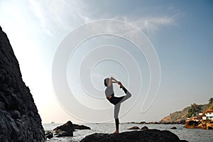 Young healthy woman practicing yoga on the beach at sunset