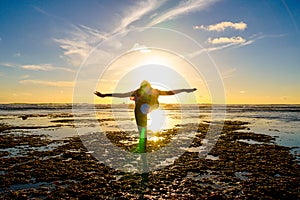 Young healthy woman practicing yoga on the beach at sunset.