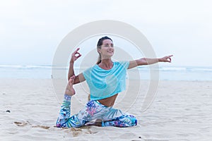 Young healthy woman practicing yoga on the beach at sunset