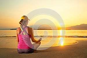 Young healthy woman practicing yoga on the beach at sunset