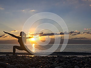 Young healthy woman practicing yoga fitness exercise on the beach at sunset. Healthy lifestyle concept. Copy space text.