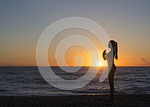 Young healthy woman practicing yoga fitness exercise on the beach at sunset. Healthy lifestyle concept. Copy space text.