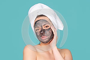 Young healthy woman in spa making treatments and face mask. Beautiful woman with cosmetic mud facial procedure, spa