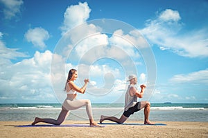 Young healthy Yoga woman and man workout yoga pose on the beach at sunset