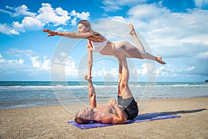 Young healthy Yoga woman and man workout yoga pose on the beach at sunset