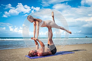 Young healthy Yoga woman and man workout yoga pose on the beach at sunset