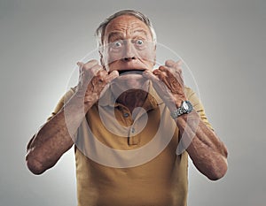 Always young at heart. Studio shot of an elderly man making a funny face against a grey background.