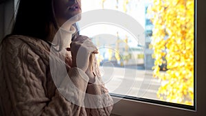 Young helpless woman praying, sitting on window sill, God faith, loneliness