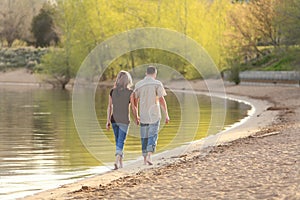 Young heterosexual couple walking on beach rear view