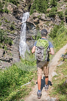 Young hiker with backpack on a mountain path, Lillaz waterfalls near Cogne, Gran Paradiso national park, Aosta Valley the Alps,