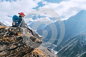 Young hiker backpacker female sitting on cliff edge and enjoying the Imja Khola valley during high altitude Everest Base Camp EBC