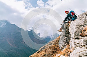 Young hiker backpacker female sitting on cliff edge and enjoying the Imja Khola valley during high altitude Everest Base Camp EBC