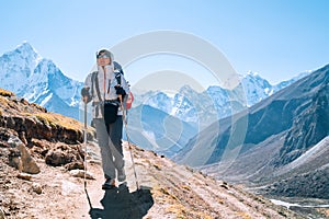 Young hiker backpacker female taking a walking with trekking poles during high altitude Everest Base Camp route near Dingboche,