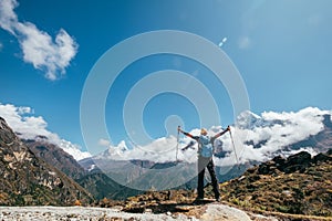 Young hiker backpacker man rising arms with trekking poles enjoying the Thamserku 6608m mountain during high altitude