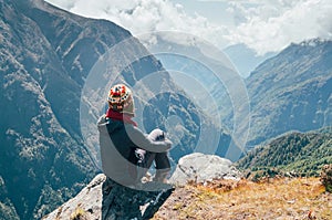 Young hiker backpacker sitting on the peak edge and enjoying mountains view valley during high altitude Everest Base Camp EBC photo