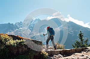 Young hiker backpacker woman using trekking poles enjoying Everest Base Camp trekking route with Thamserku 6608m mountain on