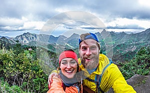 Young hiker couple taking selfie photo at peak of the mountain - Happy millennial people having fun in tour excursion - Travel,