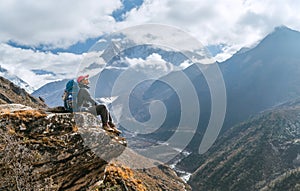 Young hiker female backpacker sitting on the cliff edge and enjoying Ama Dablam 6,812m peak view during Everest Base Camp EBC