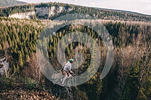 Young hiker looking down from a top of a mountain