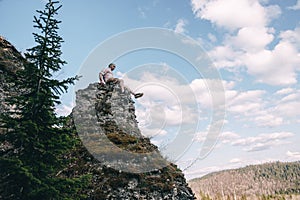 Young hiker looking down from a top of a mountain