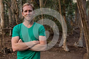 Young hiker man with folded hands standing in the forest on a sunny day