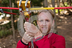 Young hiker man holding zip line pulley in the forest during daytime