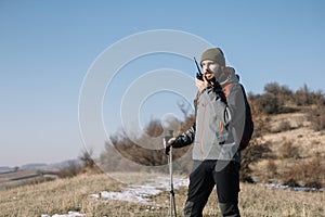 Young hiker man speaking on mountain walkie-talkie