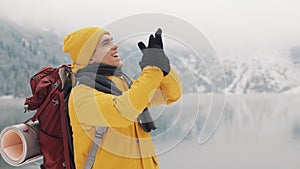 Young hiker man standing on top of the mountain. Traveller man raising hands. Successful and winner Concept. Winter time