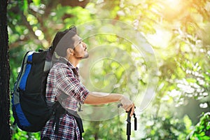 Young hiker man stop for a rest during looking at the trees around. Adventure travel.