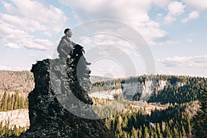 Young hiker sitting and relaxing on top of a mountain
