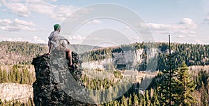 Young hiker sitting and relaxing on top of a mountain