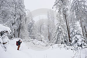 Young hiker taking pictures of a snow covered forest