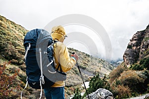 Young hiker traveling across hazy mountain. Man tourist walk by foggy rocky track wearing backpack